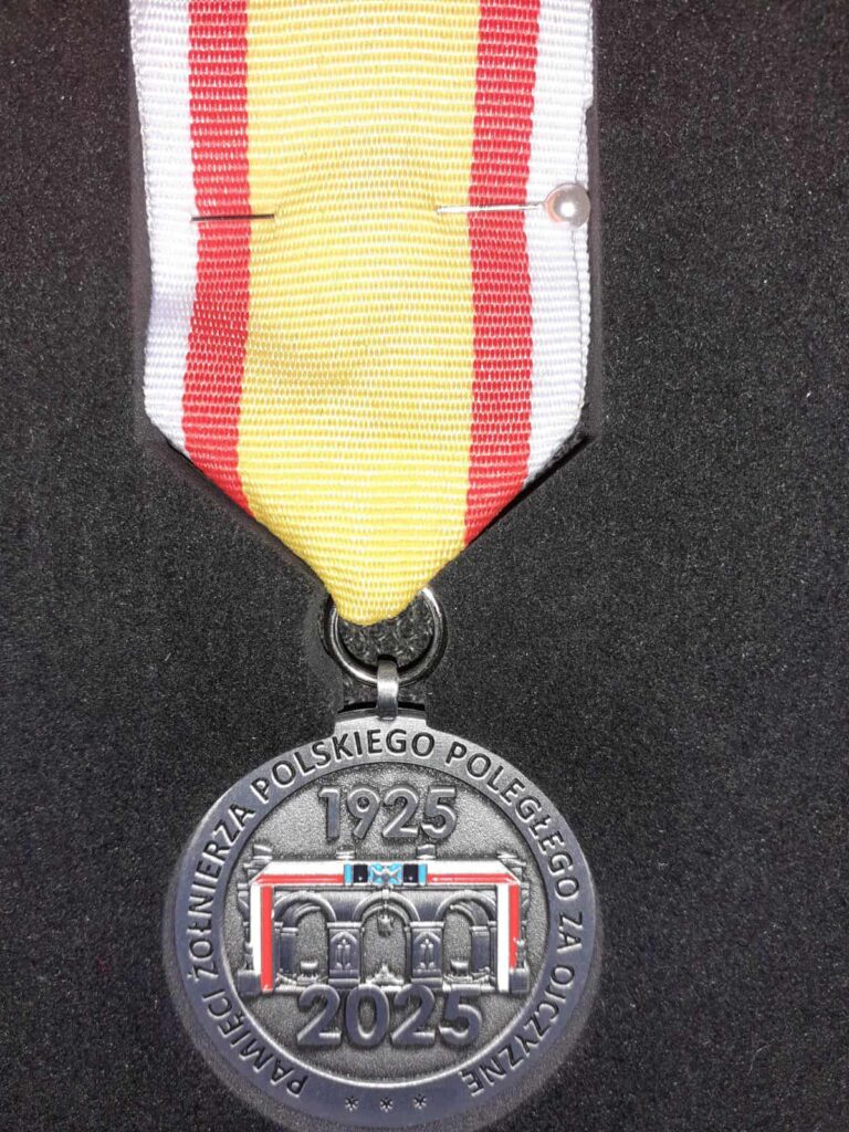 Medal o kształcie okrągłym, srebrny, z napisem: pamięci żołnierza polskiego poległego za ojczyznę 1925-2025, na wstążce w kolorze żółtym z biało-czerwonymi paskami, medal jest przypięty do garnituru w kolorze stalowym