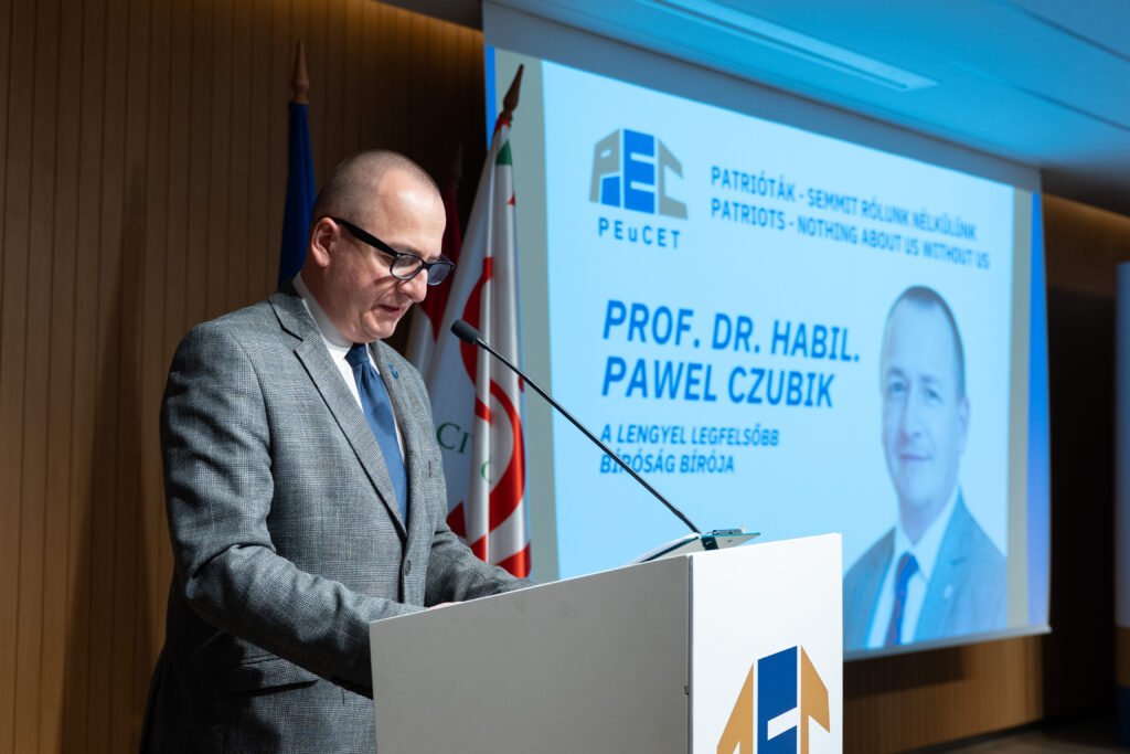 Prof. Czubik przemawia przy mównicy, w tle widać ekran z prezentacją