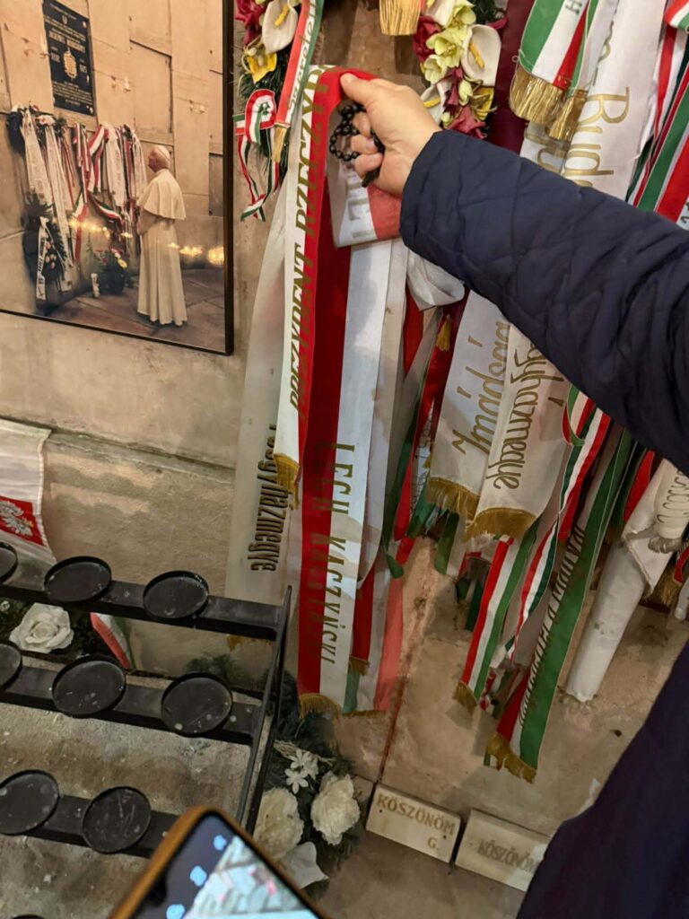 Mężczyzna trzyma szarfę przy grobie krad. Mindszentego