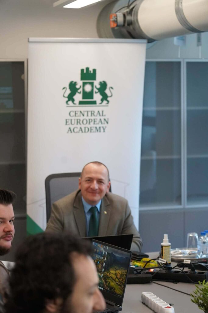 Prof. Czubik siedzi przy stole w otoczeniu studentów