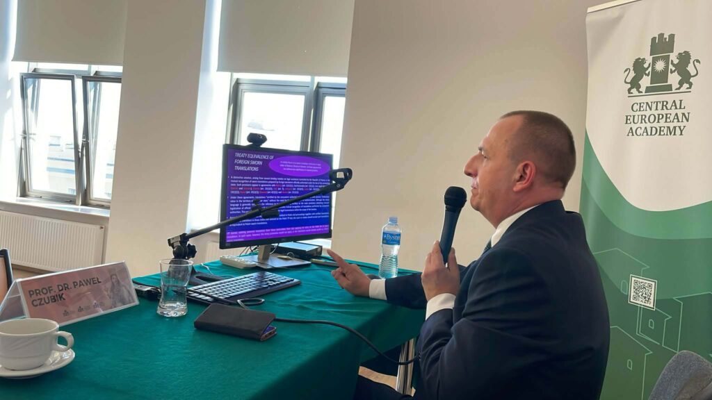 Profesor wygłasza wykład siedząc przy stole w sali konferencyjnej