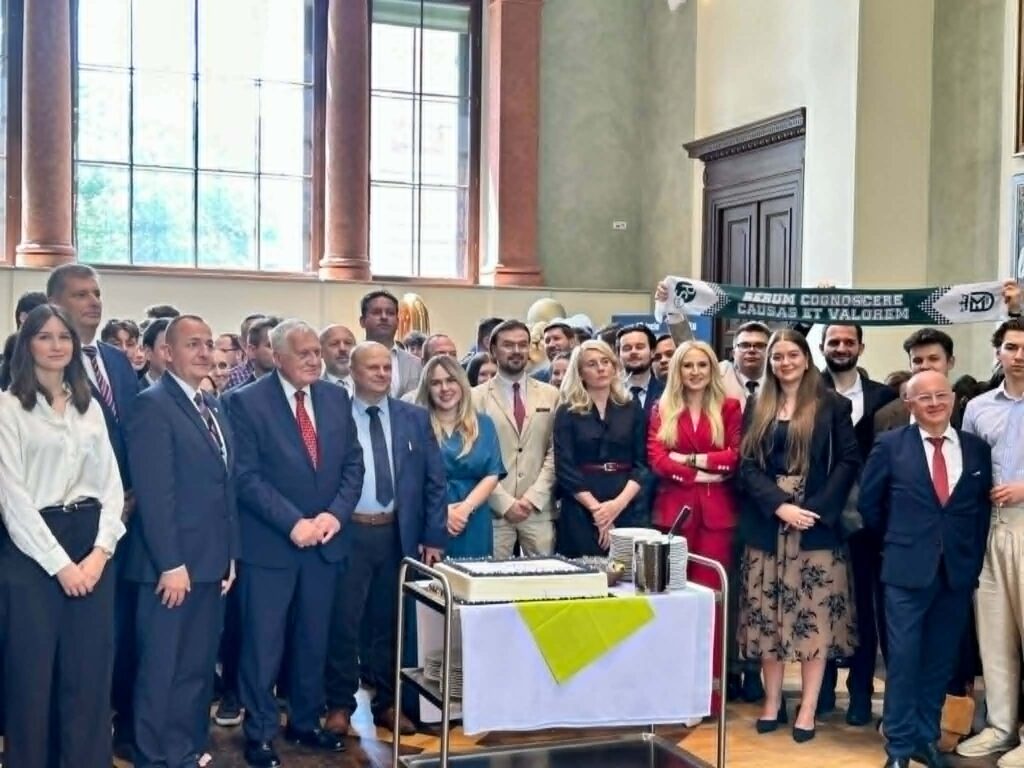 grupa osób stoi w auli uniwersyteckiej świętując jubileusz