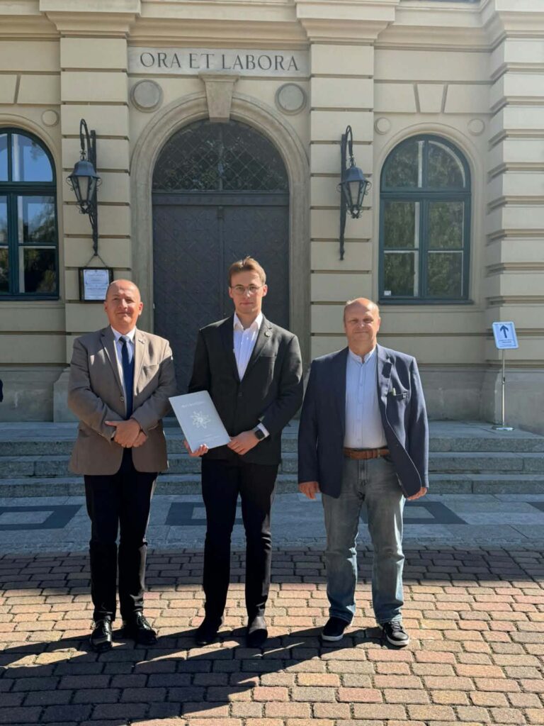 grupa trzech osób stoi przed budynkiem uniwersytetu