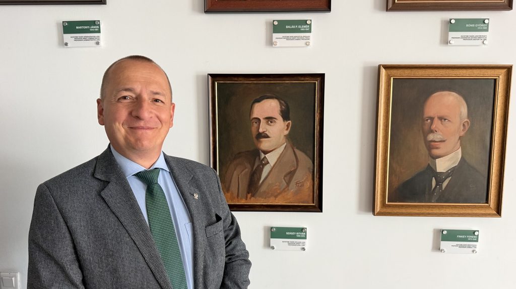 mężczyzna stoi obok dwóch portretów