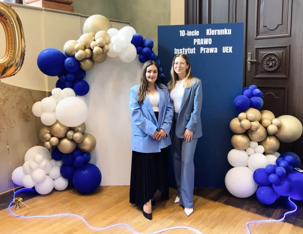 dwie kobiety w niebieskich marynarkach, obok granatowe, złote i białe balony