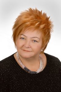 Kobieta o krótkich włosach, ubrana w elegancki, czarny swetr. Fryzura podkreśla jej pewność siebie i nowoczesny styl.